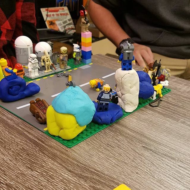 a model neighborhood on a table made of Lego people, Legos, and Play-Doh