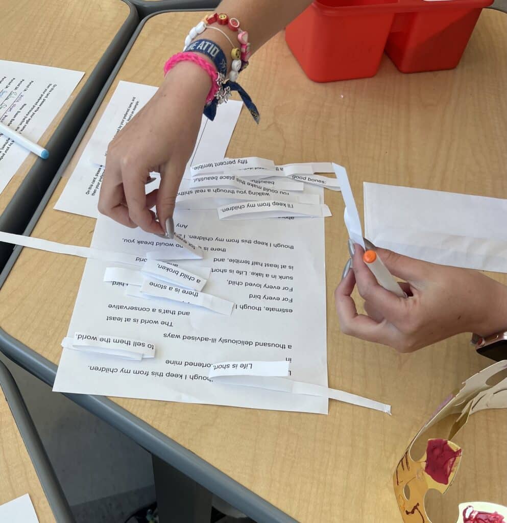A student's hand arranging strips of paper with words on them onto another sheet of paper